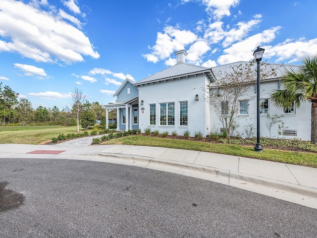 view of front of property with a front yard, metal roof, and stucco siding