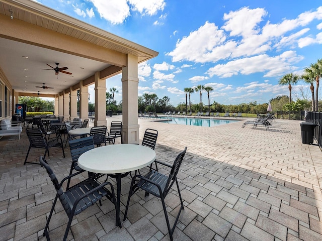 view of patio / terrace with outdoor dining area, ceiling fan, a community pool, and fence