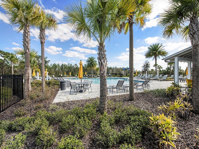 community pool with a patio area and fence