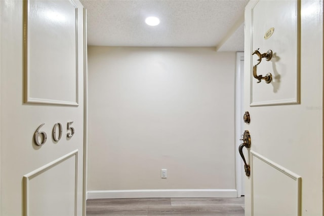 interior space featuring a textured ceiling, light wood finished floors, and baseboards