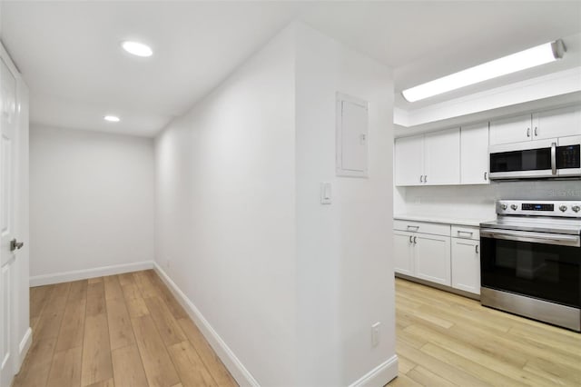 kitchen with electric panel, light wood finished floors, white cabinets, and stainless steel range with electric cooktop
