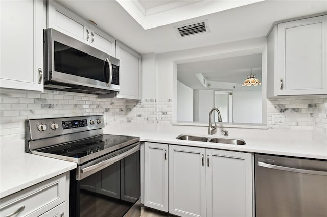 kitchen with a sink, visible vents, a raised ceiling, and appliances with stainless steel finishes