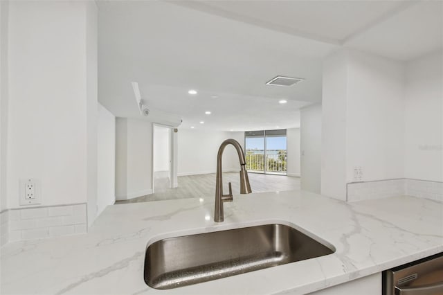 kitchen with visible vents, a sink, open floor plan, light stone countertops, and dishwasher