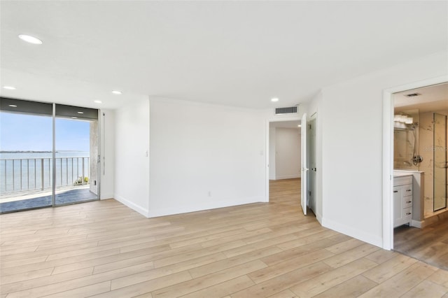 spare room with visible vents, baseboards, a wall of windows, light wood-type flooring, and recessed lighting
