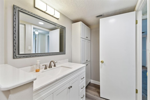 bathroom featuring vanity, wood finished floors, visible vents, and a textured ceiling