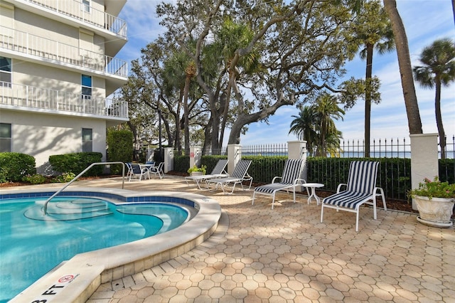 view of swimming pool featuring a patio, a swimming pool, and fence