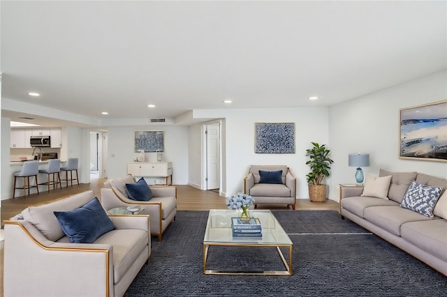 living area with recessed lighting, visible vents, and wood finished floors