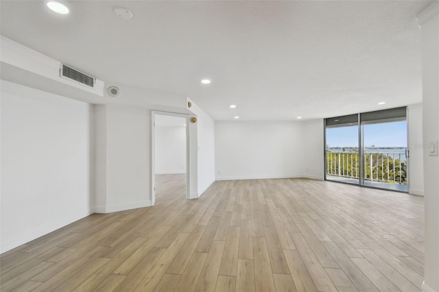 spare room with baseboards, visible vents, recessed lighting, floor to ceiling windows, and light wood-type flooring
