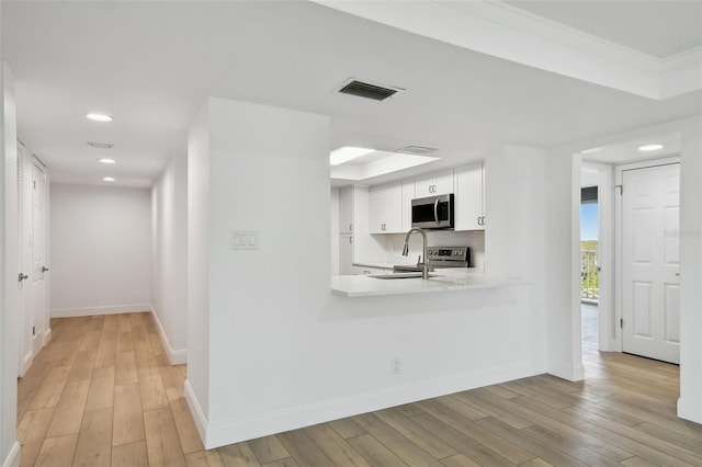 kitchen with visible vents, light wood-style flooring, a sink, light countertops, and stainless steel microwave
