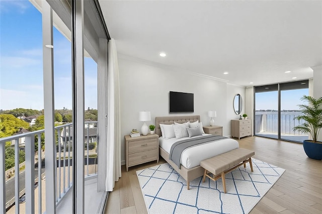 bedroom featuring access to exterior, floor to ceiling windows, light wood-style floors, and ornamental molding