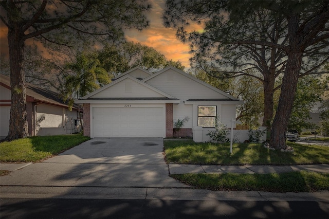 ranch-style home with an attached garage, driveway, a front lawn, and brick siding