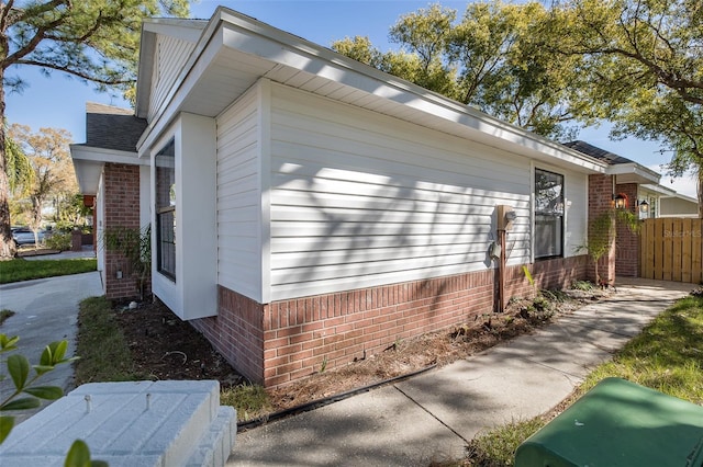 view of side of property featuring brick siding and fence