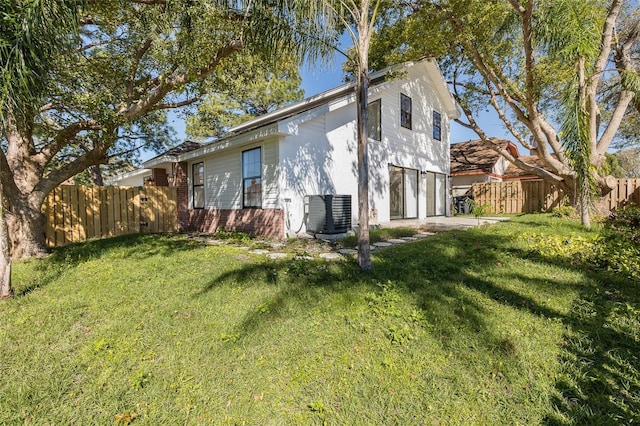 view of side of home with a garage, a lawn, fence, and central AC