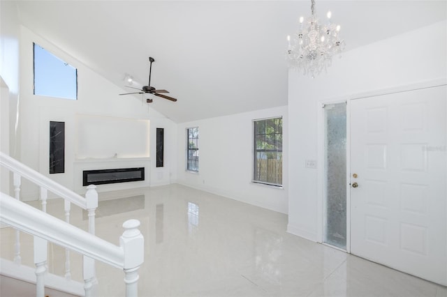 unfurnished living room featuring high vaulted ceiling, ceiling fan with notable chandelier, stairway, and a glass covered fireplace