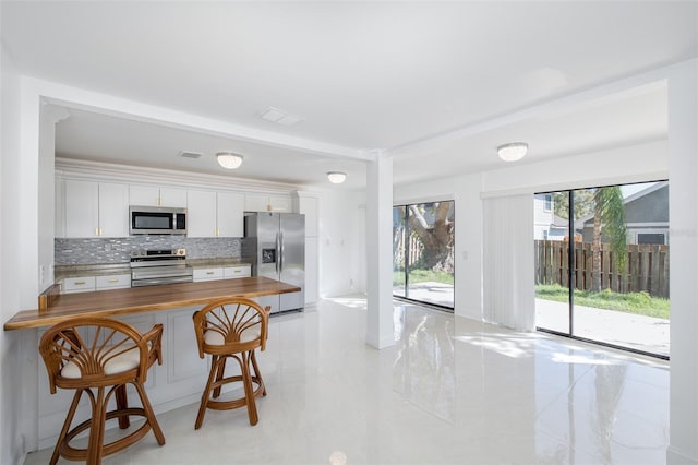 kitchen with stainless steel appliances, visible vents, backsplash, white cabinets, and wood counters