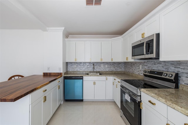 kitchen with stainless steel appliances, wood counters, a sink, visible vents, and backsplash