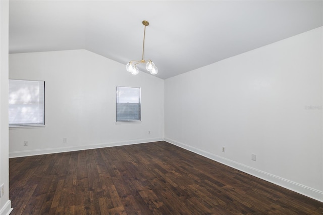 spare room featuring an inviting chandelier, baseboards, vaulted ceiling, and dark wood-style flooring