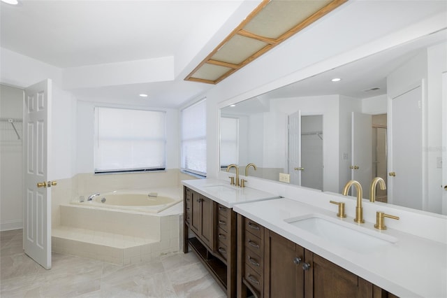 bathroom with a spacious closet, double vanity, a sink, and a bath