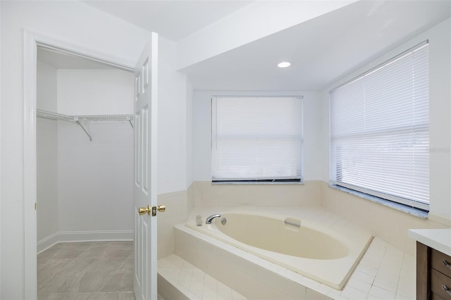 bathroom featuring a garden tub, recessed lighting, a spacious closet, and vanity