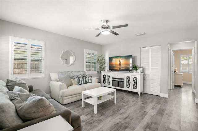 living area with visible vents, wood finished floors, baseboards, and ceiling fan