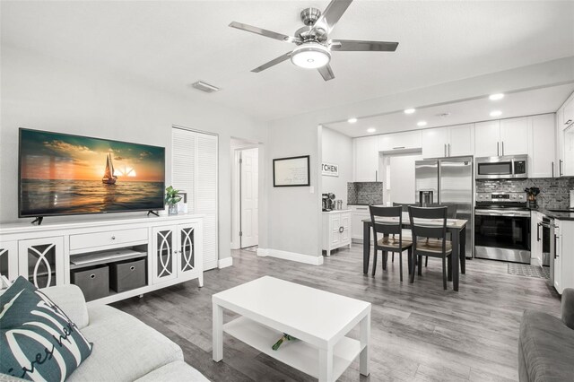 living room featuring baseboards, visible vents, recessed lighting, ceiling fan, and light wood-type flooring