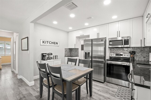 kitchen with decorative backsplash, light wood finished floors, visible vents, and appliances with stainless steel finishes