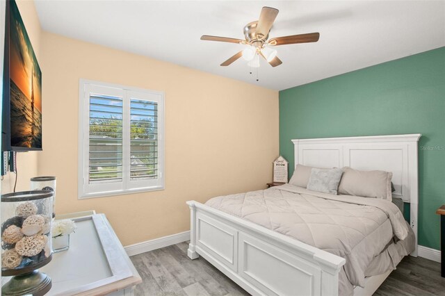 bedroom featuring light wood finished floors, a ceiling fan, and baseboards