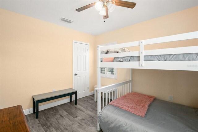 bedroom with a ceiling fan, wood finished floors, visible vents, and baseboards