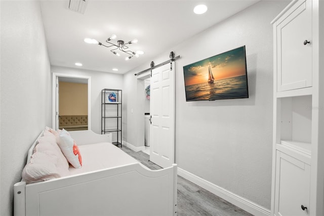 bedroom with baseboards, ensuite bath, light wood-style flooring, recessed lighting, and a barn door