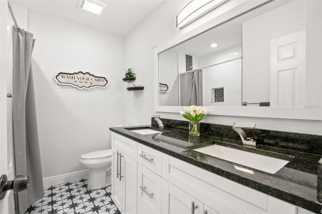 bathroom with double vanity, toilet, baseboards, and a sink