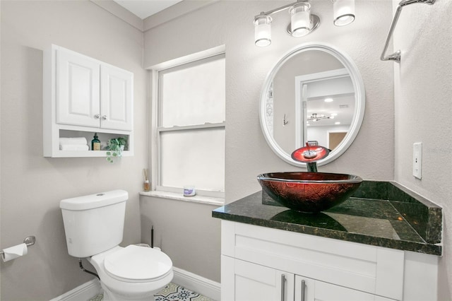 half bath with vanity, toilet, and baseboards