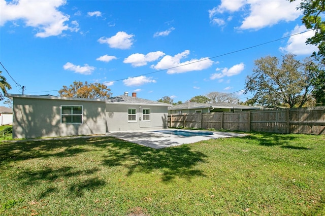 rear view of house featuring a yard, stucco siding, a patio, and a fenced backyard