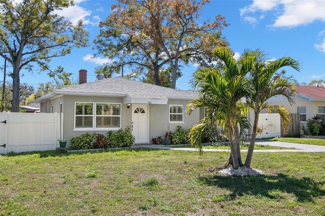 view of front of property with a front lawn, fence, and stucco siding