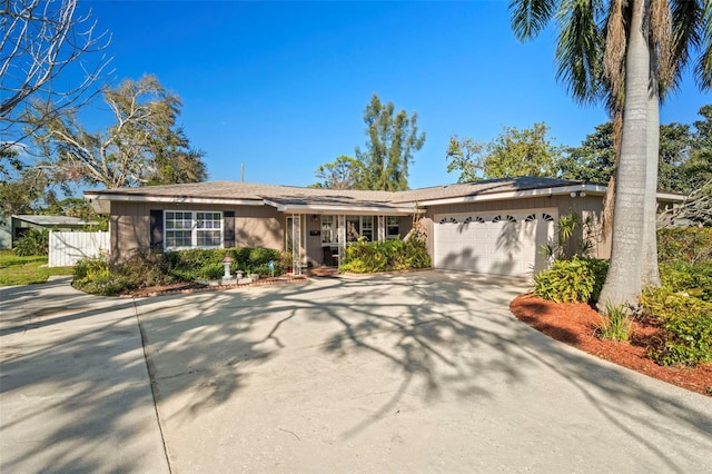 ranch-style house with an attached garage, driveway, and fence