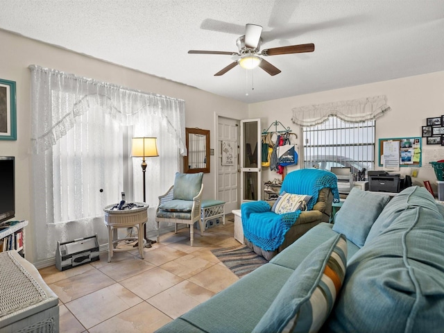 living room with ceiling fan, a textured ceiling, and tile patterned floors