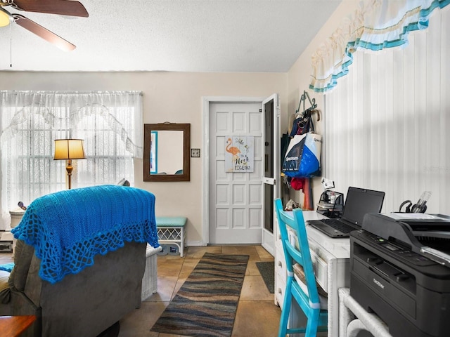 bedroom featuring a ceiling fan, a textured ceiling, baseboards, and tile patterned floors