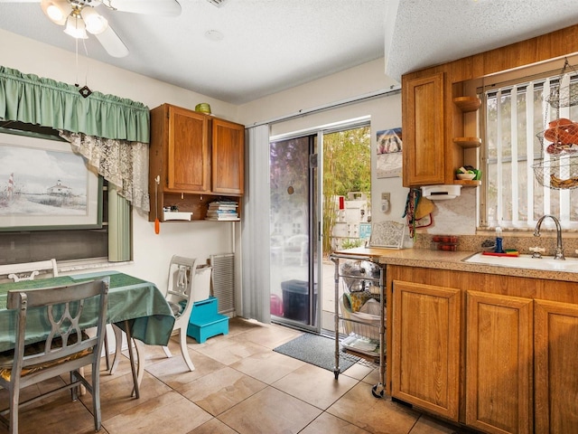 kitchen with open shelves, a sink, light countertops, and brown cabinets