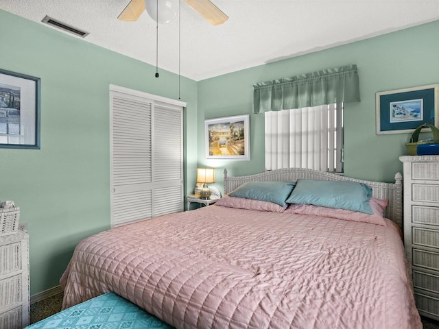 bedroom with a textured ceiling, visible vents, baseboards, a ceiling fan, and a closet