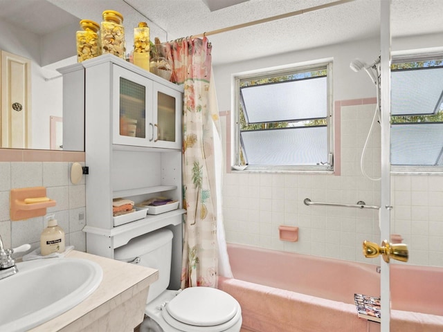 bathroom featuring a textured ceiling, toilet, a sink, and tile walls