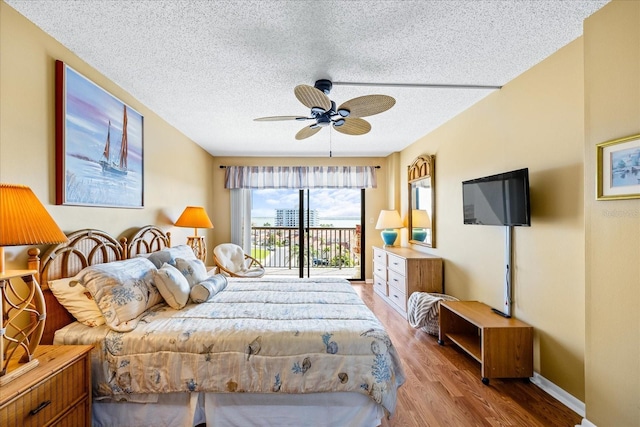 bedroom with access to outside, baseboards, light wood finished floors, and a textured ceiling