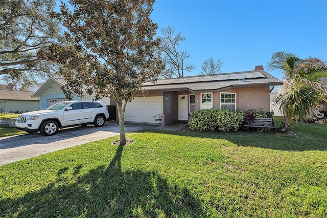 view of front of property with an attached garage, solar panels, concrete driveway, a chimney, and a front yard