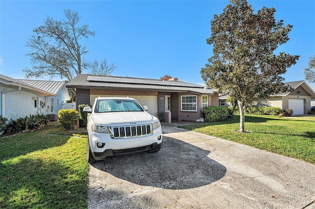 single story home featuring a garage, driveway, a front lawn, and roof mounted solar panels