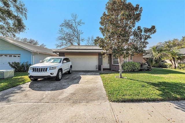 ranch-style house featuring an attached garage, driveway, a front yard, and solar panels