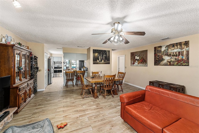 dining area with ceiling fan, light wood finished floors, a textured ceiling, and baseboards