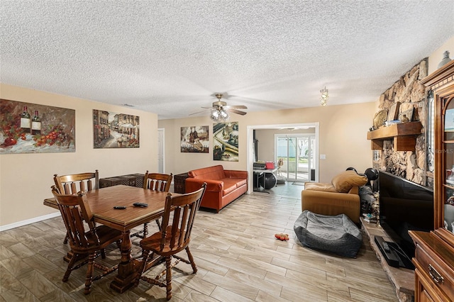 dining space with light wood-type flooring, ceiling fan, a stone fireplace, and a textured ceiling