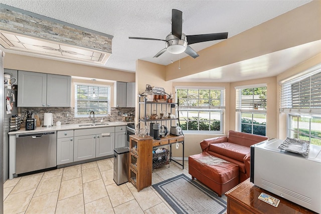 kitchen featuring decorative backsplash, dishwasher, gray cabinets, light countertops, and a sink