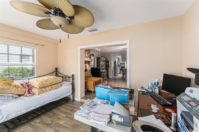 bedroom with a ceiling fan, baseboards, visible vents, and wood finished floors