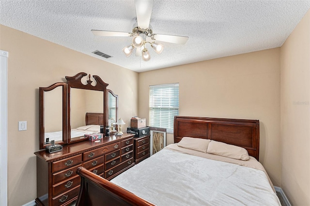 bedroom with a ceiling fan, visible vents, a textured ceiling, and baseboards