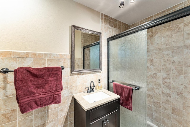 bathroom with tiled shower, vanity, and tile walls