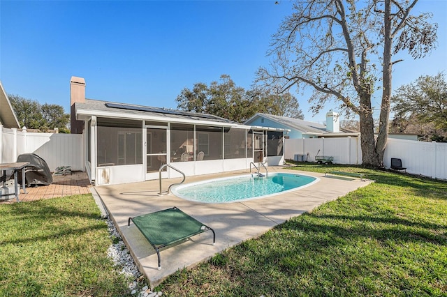 back of house with a chimney, a lawn, a sunroom, a patio area, and a fenced backyard